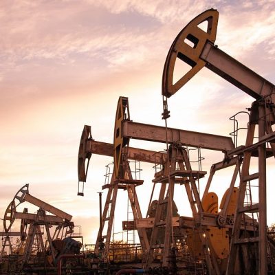 Oil pump jacks at sunset sky background. Toned.